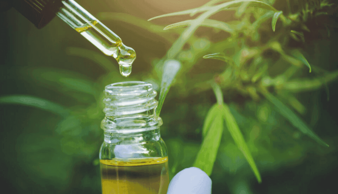 Tropfen von Hanfölen, die aus einer Flasche fallen.